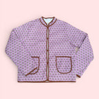 The Marley Edit pink quilted jacket with block print, round neck, button front, and tan binding. Lightweight and lined.