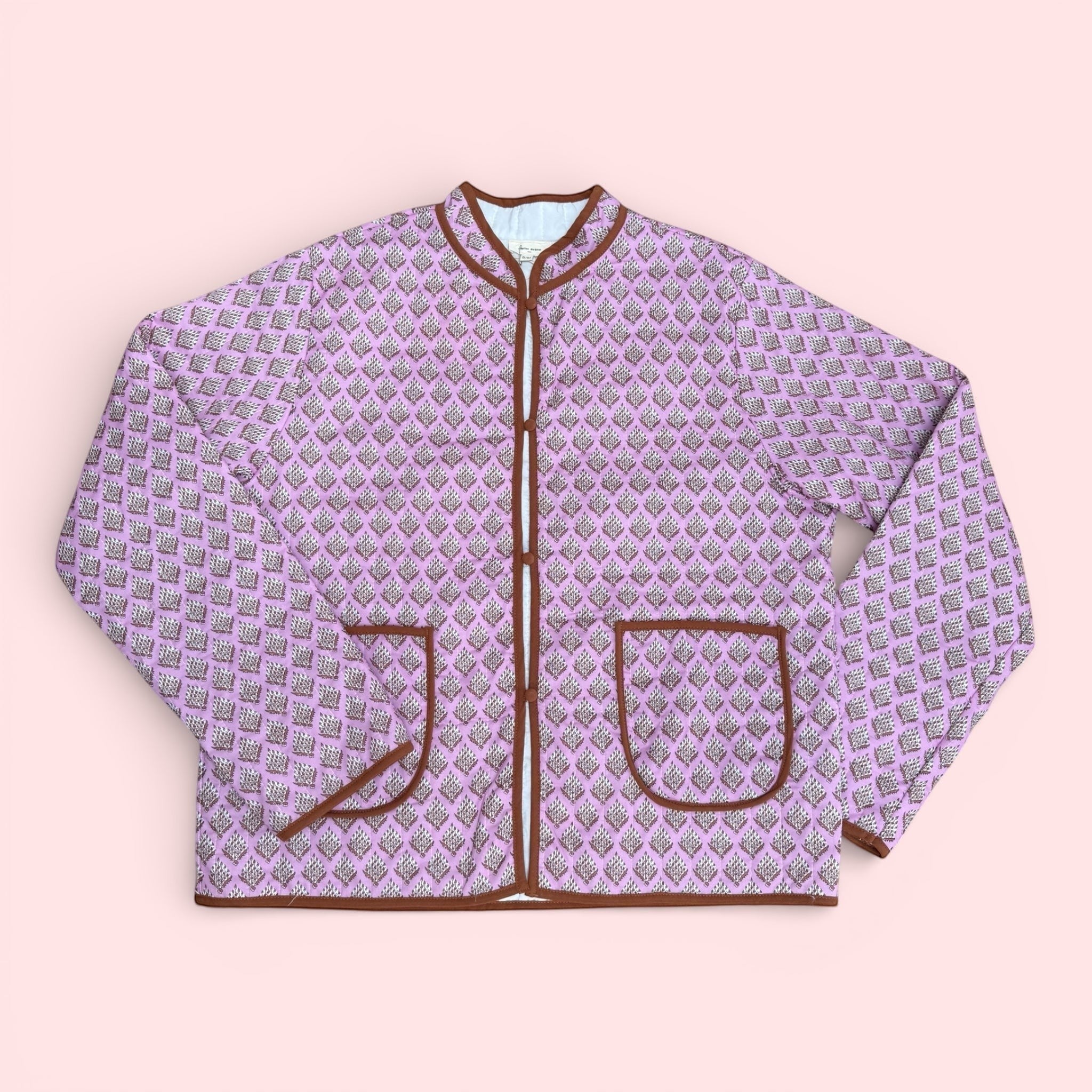 The Marley Edit pink quilted jacket with block print, round neck, button front, and tan binding. Lightweight and lined.