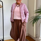 The Marley Edit pink quilted jacket with block print, tan binding, and button front, worn by a smiling woman.